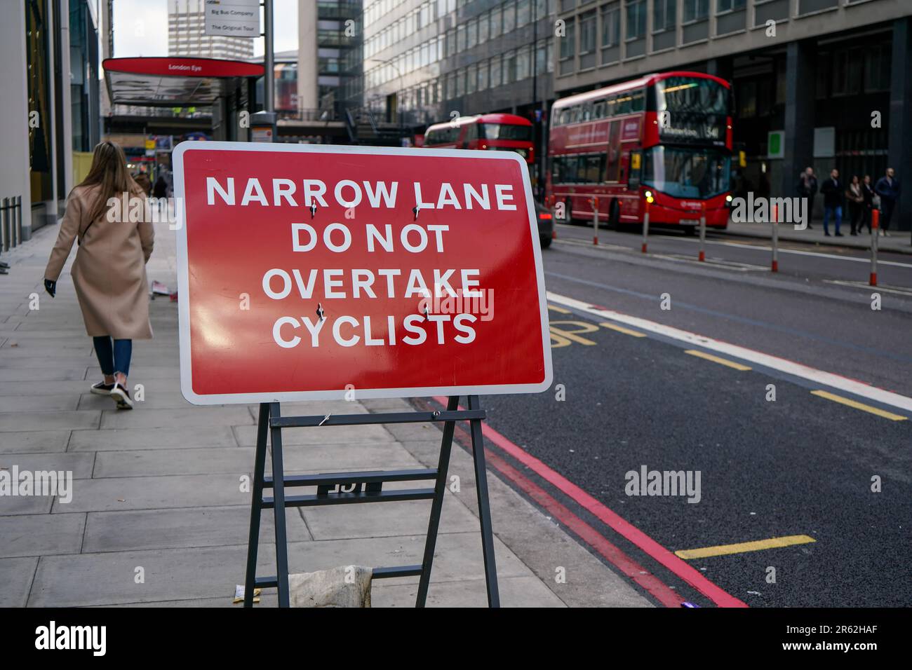 London, United Kingdom - February 02, 2019: Red road sign prompting not to overtake cyclists because of narrow road in busy city centre, tall building Stock Photo