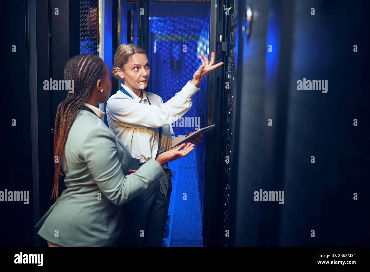Lets fix this quickly. two technicians using a digital tablet while working in a server room. Stock Photo