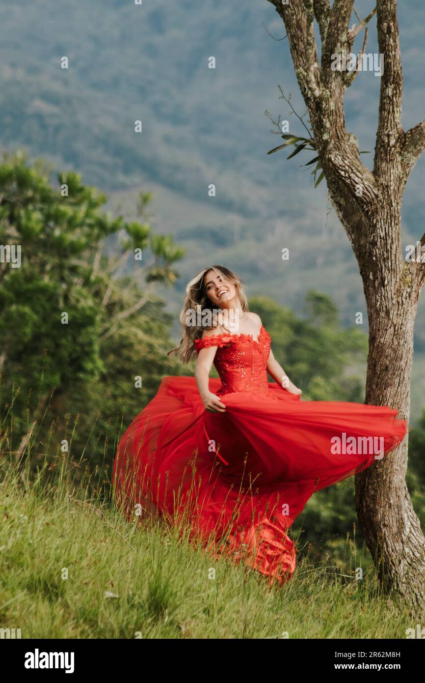 A cheerful young woman posing outdoors in a vibrant red dress Stock ...
