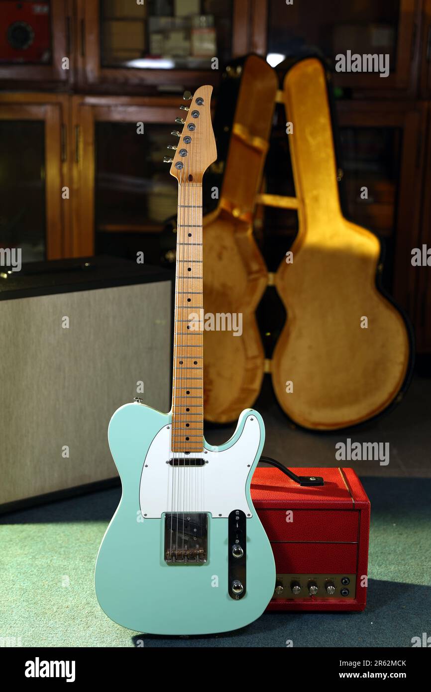 An electric guitar with green color in front of amplifier Stock Photo