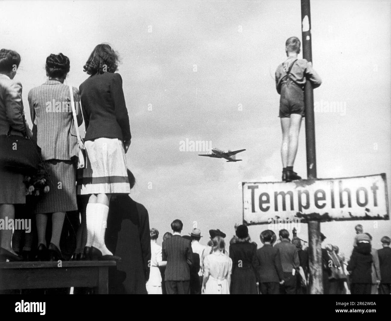 Germans watching supply planes at Tempelhof airport during the Berlin Airlift. In response escalating tensions and to the establishment of.a new West German currency, the Soviets cut off all land communications to West Berlin and stopped sending food there. TheAllied response was an eleven month campaign to supply W Berlin with the 5000 tons per day of food and fuel it needed. A plane landed every three minutes day and night and the operation was so succesful that the Soviets had to back down and reopen the roads, railways and canals. Stock Photo