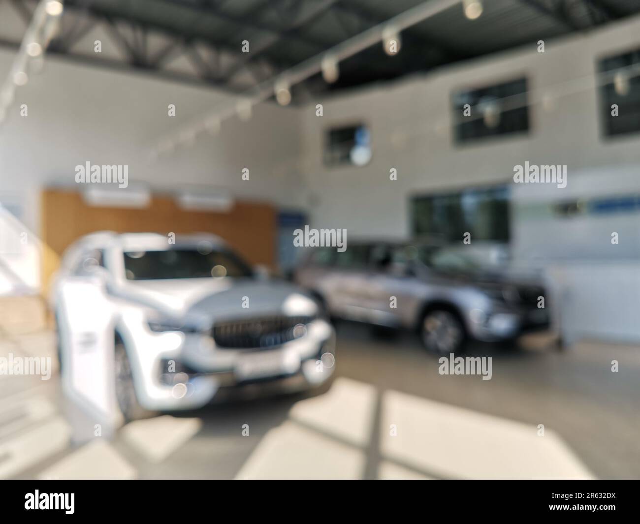 Interior of modern salon with new cars, blurred view. The sun light. Sunlight pours in through the panoramic windows. Stock Photo