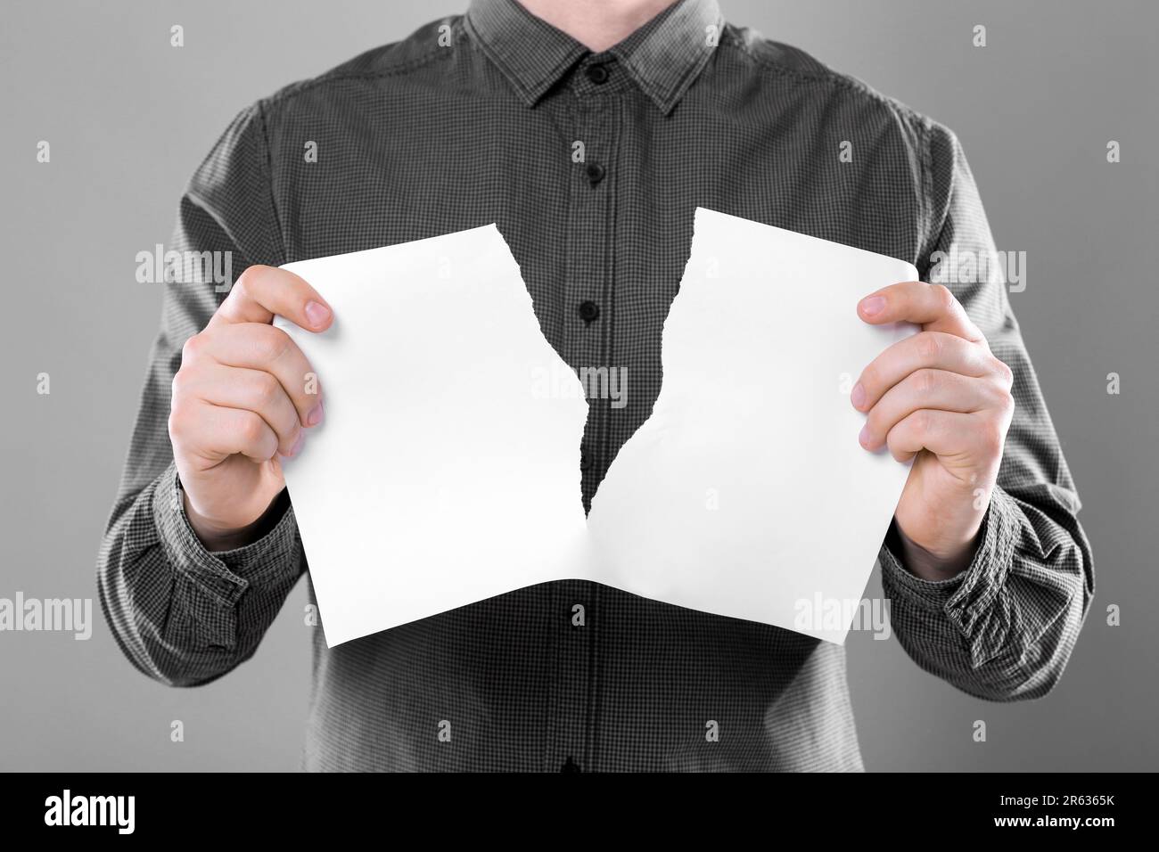 Man ripping sheet of paper on grey background, closeup. Mockup for