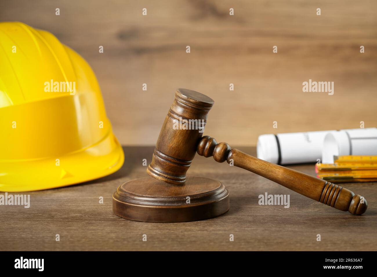 Construction and land law concepts. Judge gavel, protective helmet with drawings on wooden table Stock Photo
