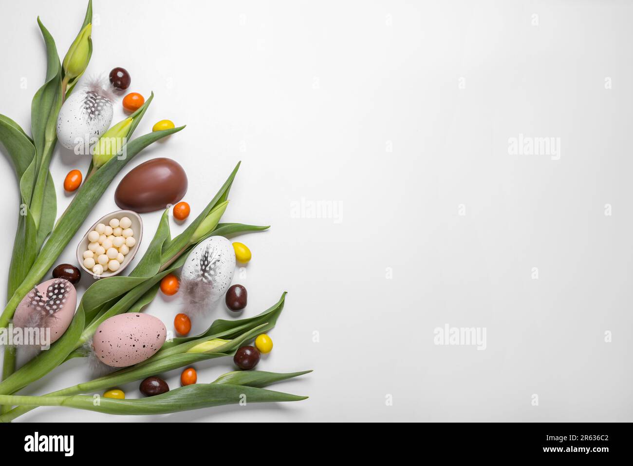 Flat lay composition with tulips, chocolate eggs and candies on white ...