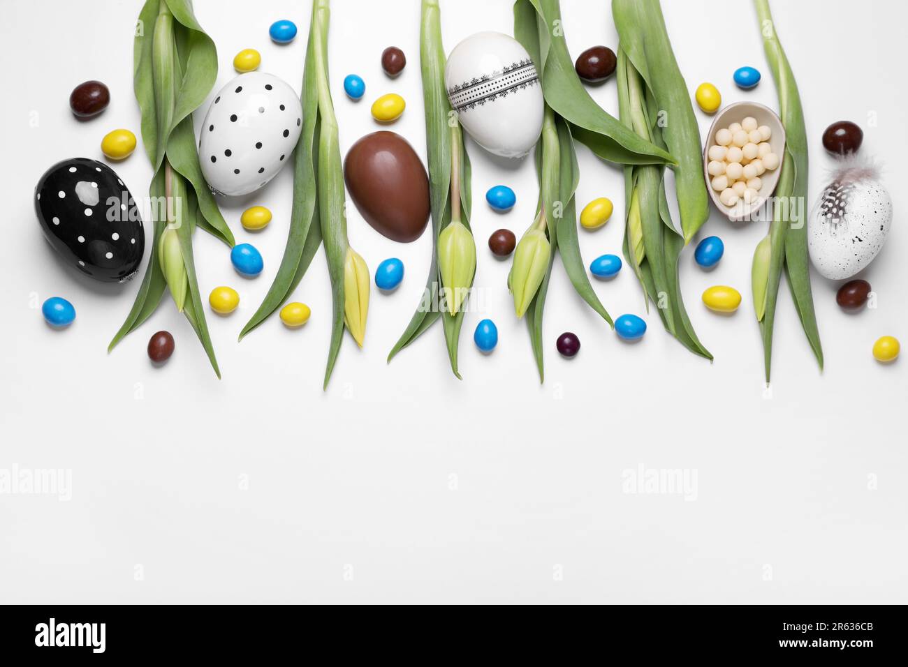 Flat lay composition with tulips, chocolate eggs and candies on white ...