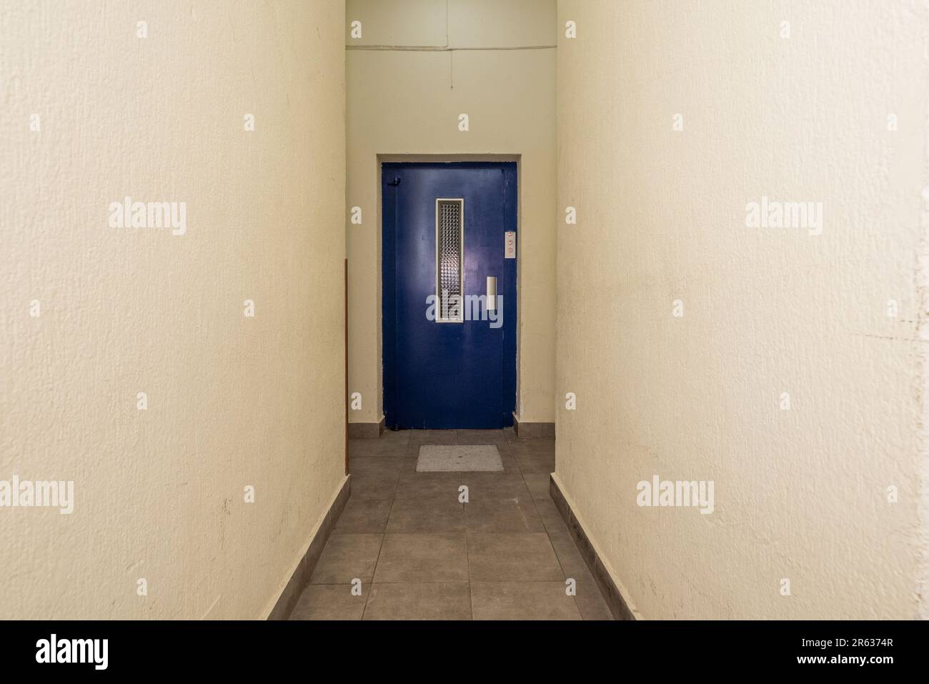 Corridor of a building with access to an elevator with a blue metal door Stock Photo