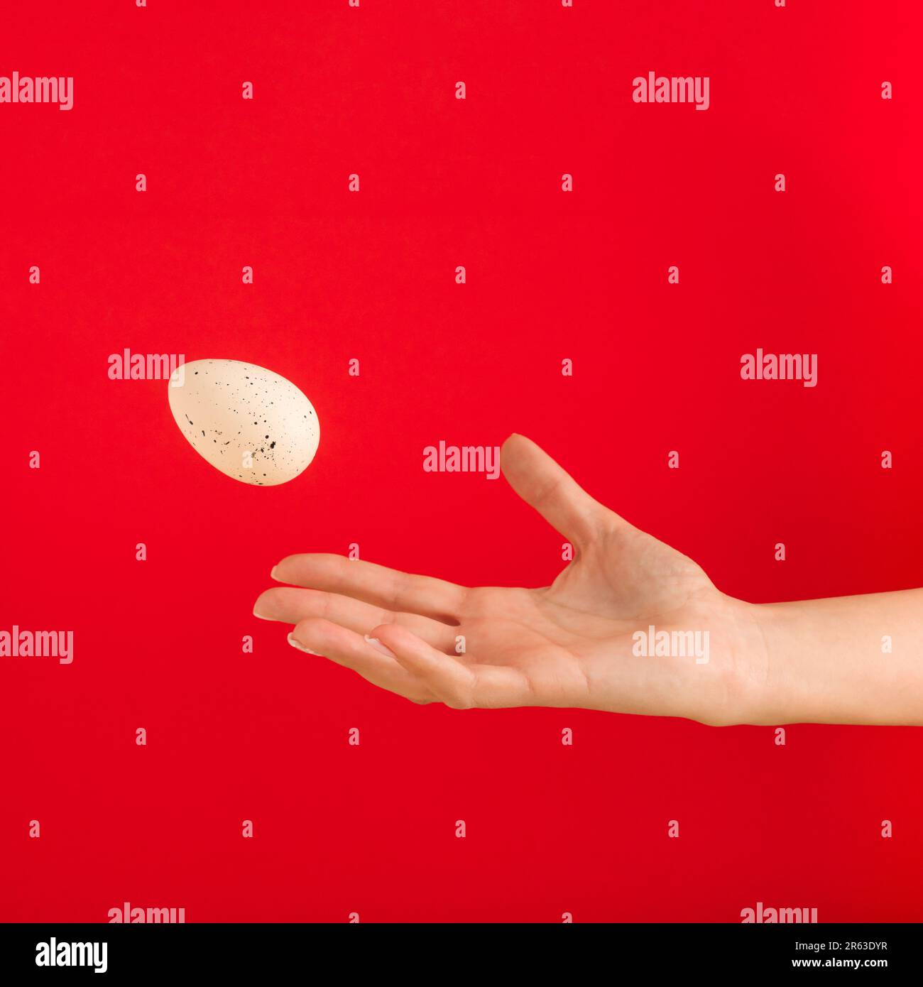 Woman's hand throwing away white egg on red background. Minimal Easter