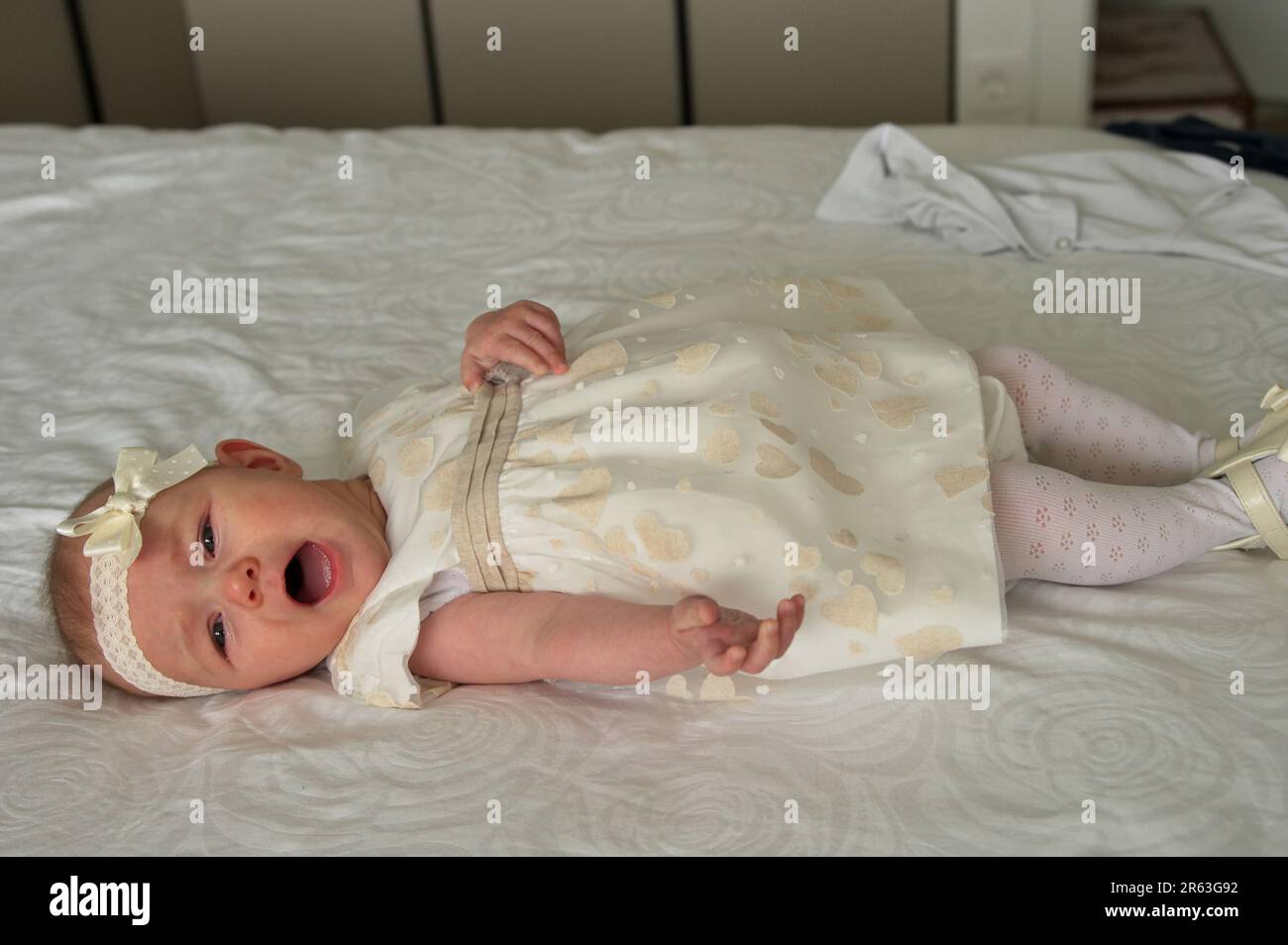 Little baby girl dressed for christening lying on a bed Stock Photo Alamy
