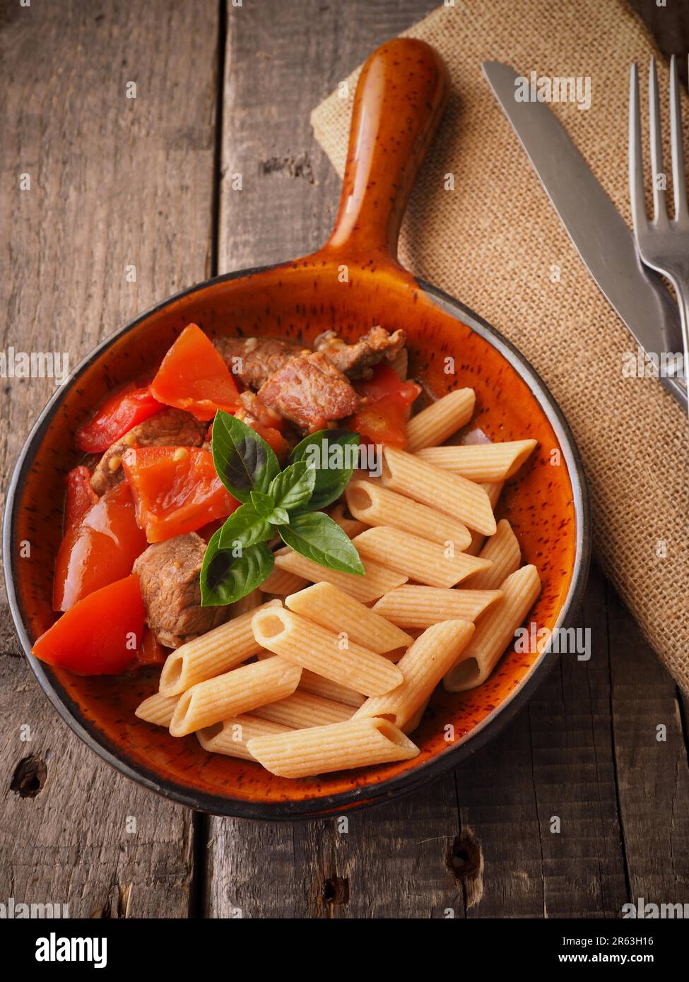 Tasty goulash with whole grain penne in a rustic pan Stock Photo
