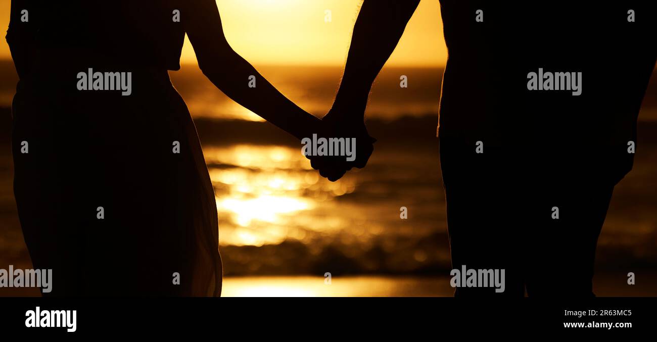 Silhouette, couple and holding hands at sunset on beach for vacation or ...