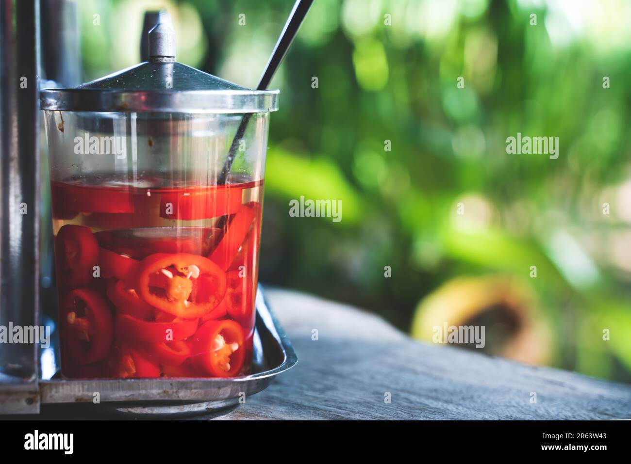 Pickled sliced chillies in a glas with tropical sunny setting in an Asian restaurant as an ingredient for spicing up your dish Stock Photo