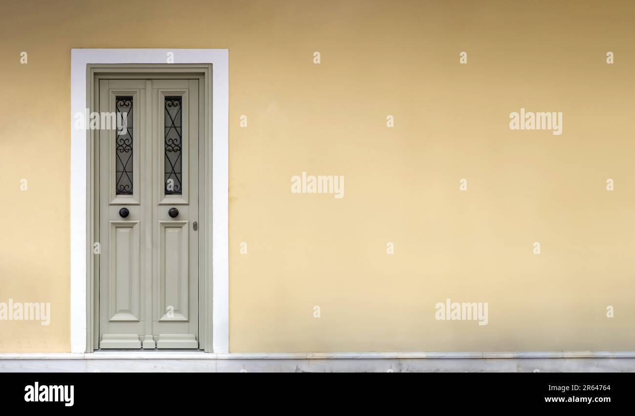 Wooden entrance door with white frame on an empty building wall in old town of Plaka, Athens Greece Stock Photo