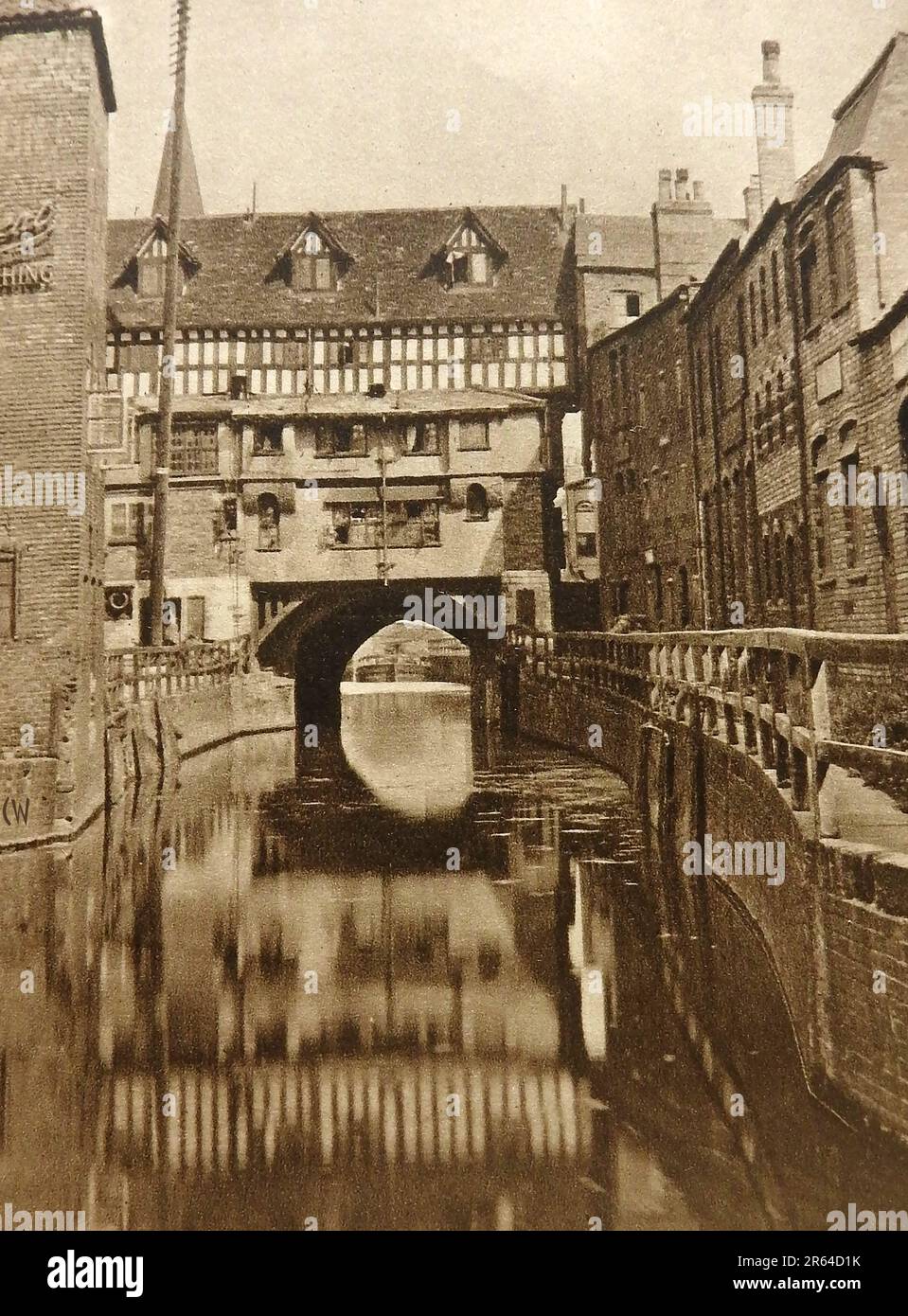 High Bridge at Lincoln England in 1933. High Bridge built around 1160.carries the High Street over the River Witham in Lincoln. It is the oldest bridge in the United Kingdom which still has buildings, once common architectural feature of ancient stone build bridges.. The present buildings upon it were rebuilt around 1901. The old bridge chapel bridge  built in 1235, was unused in 1549 due to the English Reformation and was demolished in 1762 . The opening beneath the bridge has been nicknamed the Glory Hole Stock Photo