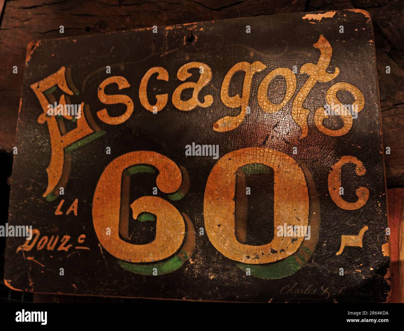 Close-up of a weathered vintage sign advertising “Escargots 60c”,reflecting traditional French cuisine and historic food pricing, with distressed text Stock Photo