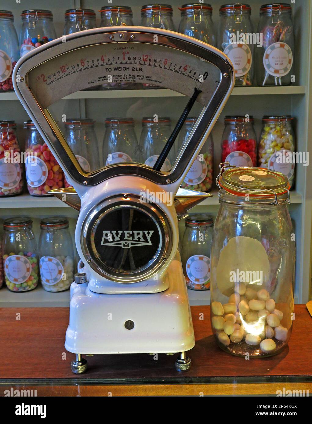 Vintage Avery weighing scales on a traditional sweet shop counter, surrounded by glass jars of confectionery, illustrating historic British retail Stock Photo