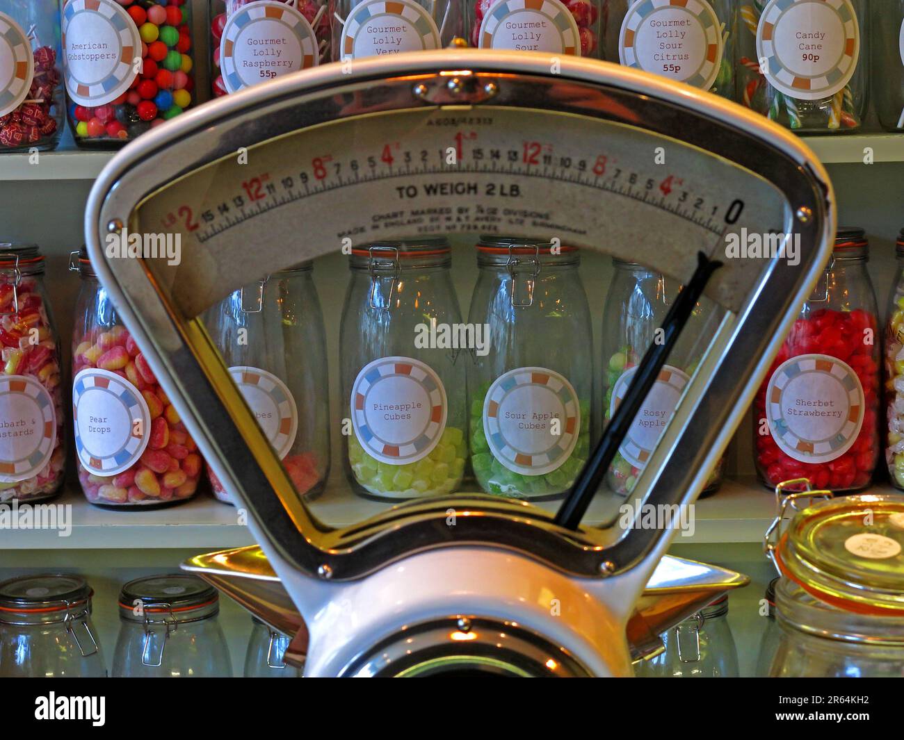 Vintage Avery weighing scales on a traditional sweet shop counter, surrounded by glass jars of confectionery, illustrating historic British retail Stock Photo
