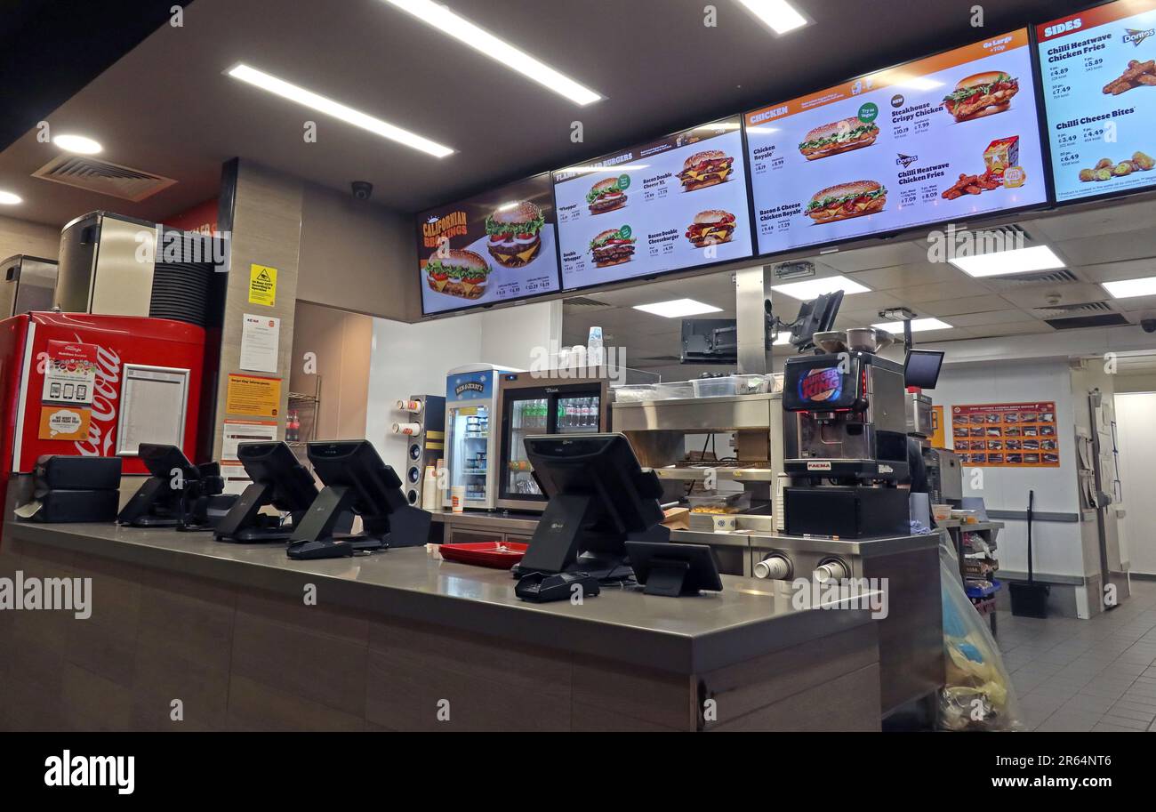 Interior of a Burger King fast food restaurant in Warrington, showing the service counter, digital menu boards, and food preparation area, Cheshire Stock Photo