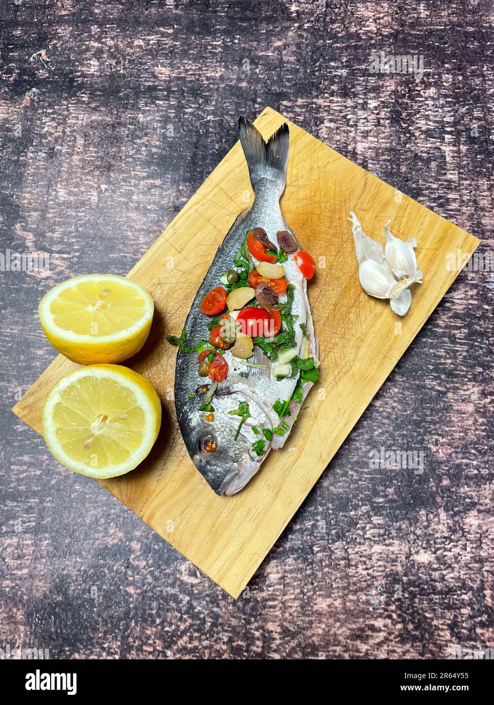 gilthead sea bream en papillote with cherry tomatoes, garlic and capers ready for cooking in the
