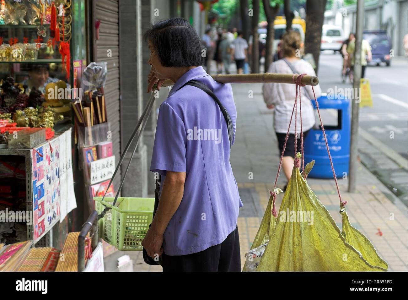 ������ �Ї� Guangzhou, China; Chinese woman carries goods on rail and watches a shop window Chinesin tr?gt die Ware auf einem Stock blickt auf Schaufenster Stock Photo
