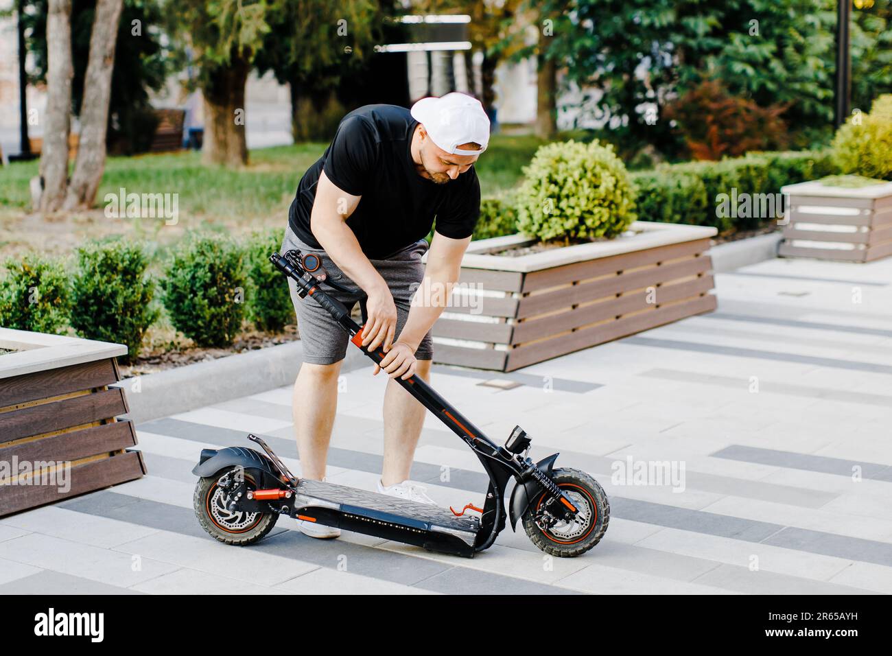 Man carry electric scooter in a folded position. Guy carrying folded E