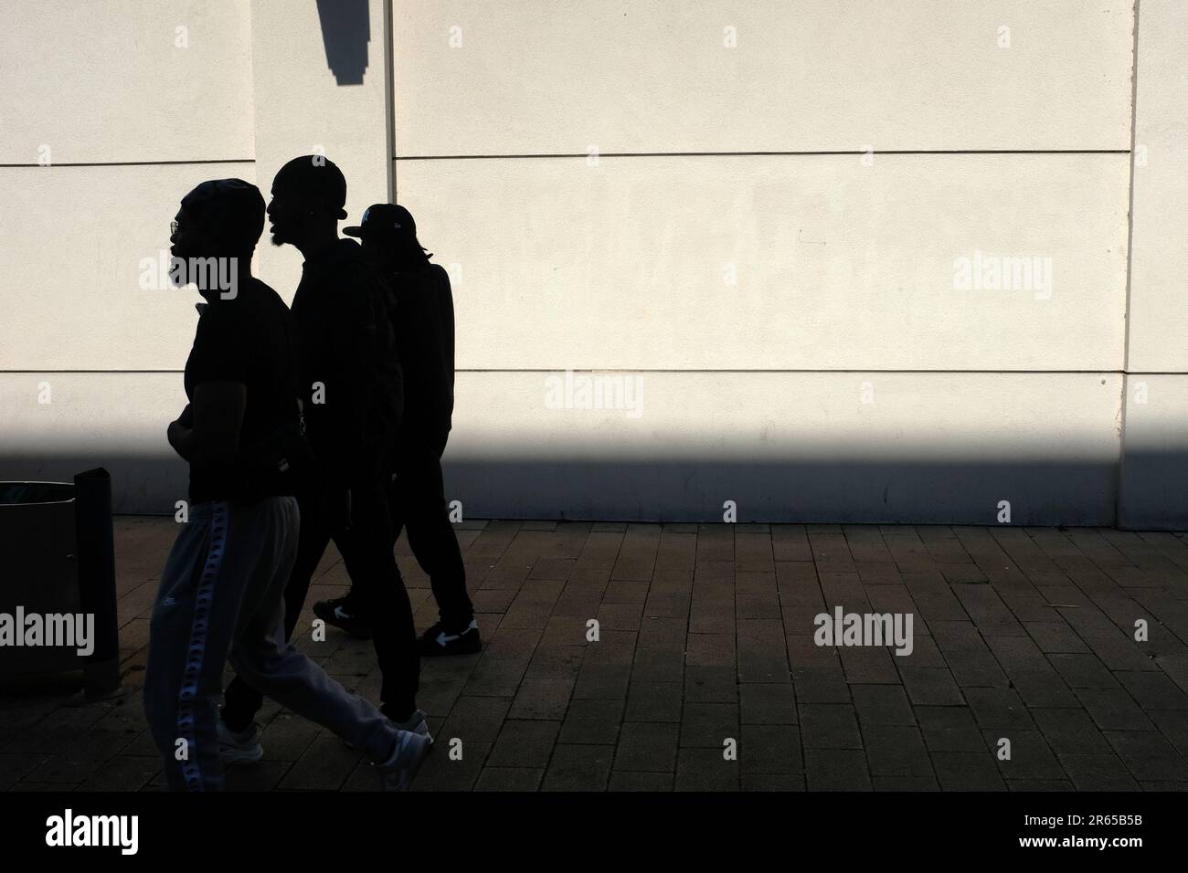 Three male, men, figures, walking together down a high street. Stock Photo