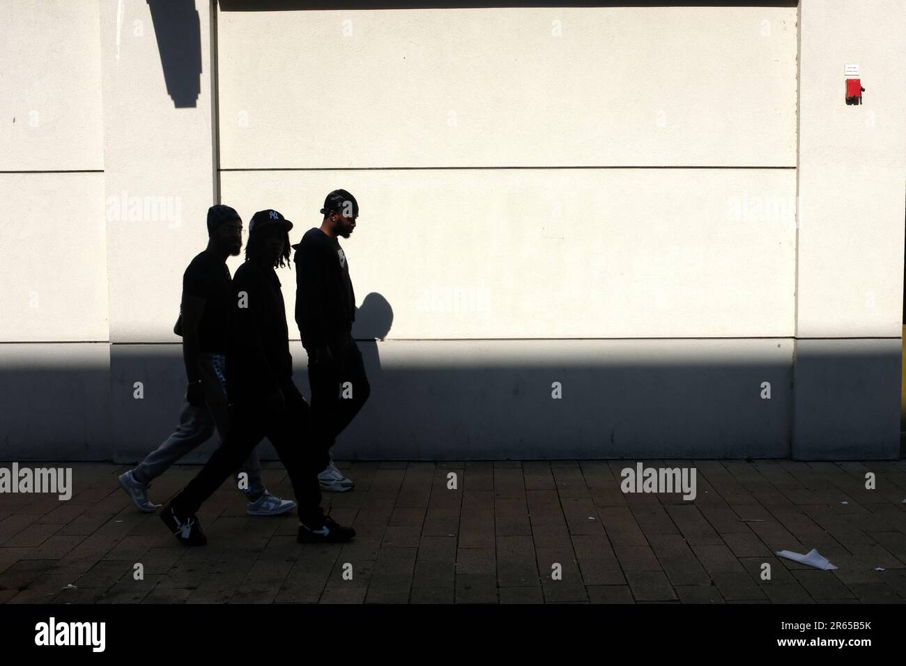 Three male, men, figures, walking together down a high street. Stock Photo