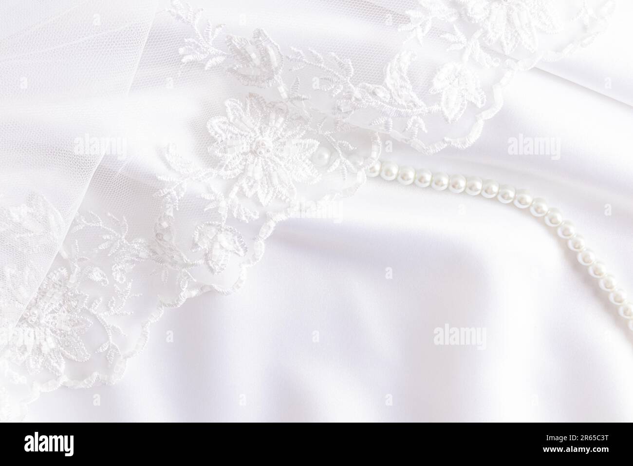 Wedding white background of abstract fabric with decor elements. white pearl beads and veil with bisser-embroidery. cover, layout, postcard Stock Photo