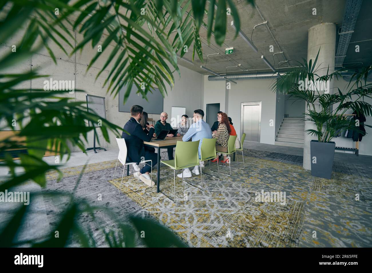 A diverse group of business professionals gathered at a modern office ...