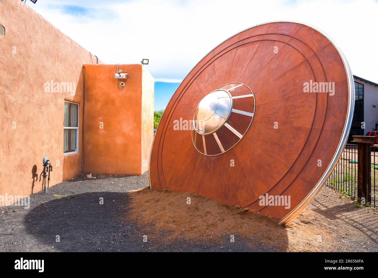 Metal sculpture of a 15' tall flying saucer that has crashed and is stuck in the earth at an odd angle, for sale by artist RT Davis, Santa Fe, NM. Stock Photo