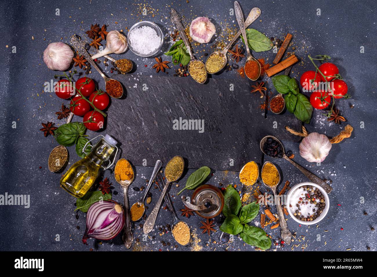 Spices for cooking on dark background . Different seasonings, spices and herbs paprika, pepper, turmeric, salt, basil, mint, cinnamon, garlic, olive o Stock Photo