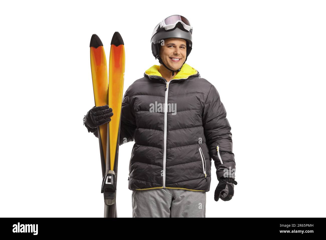 Man in a skiing jacket and boots holding pair of skis isolated on a white background Stock Photo