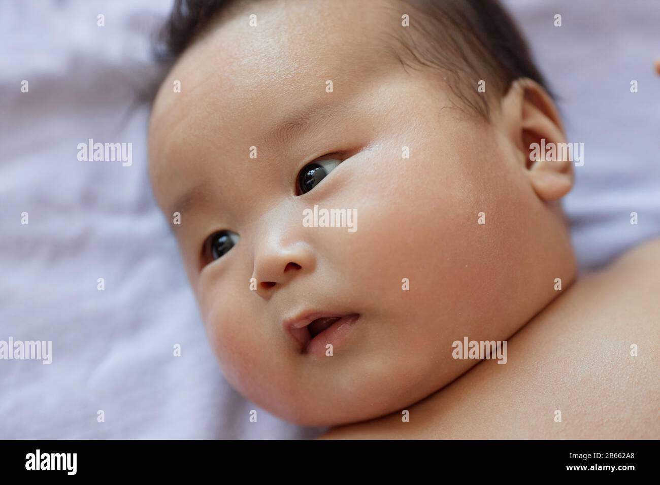 Close-up of Asian newborn baby lying in his cot Stock Photo