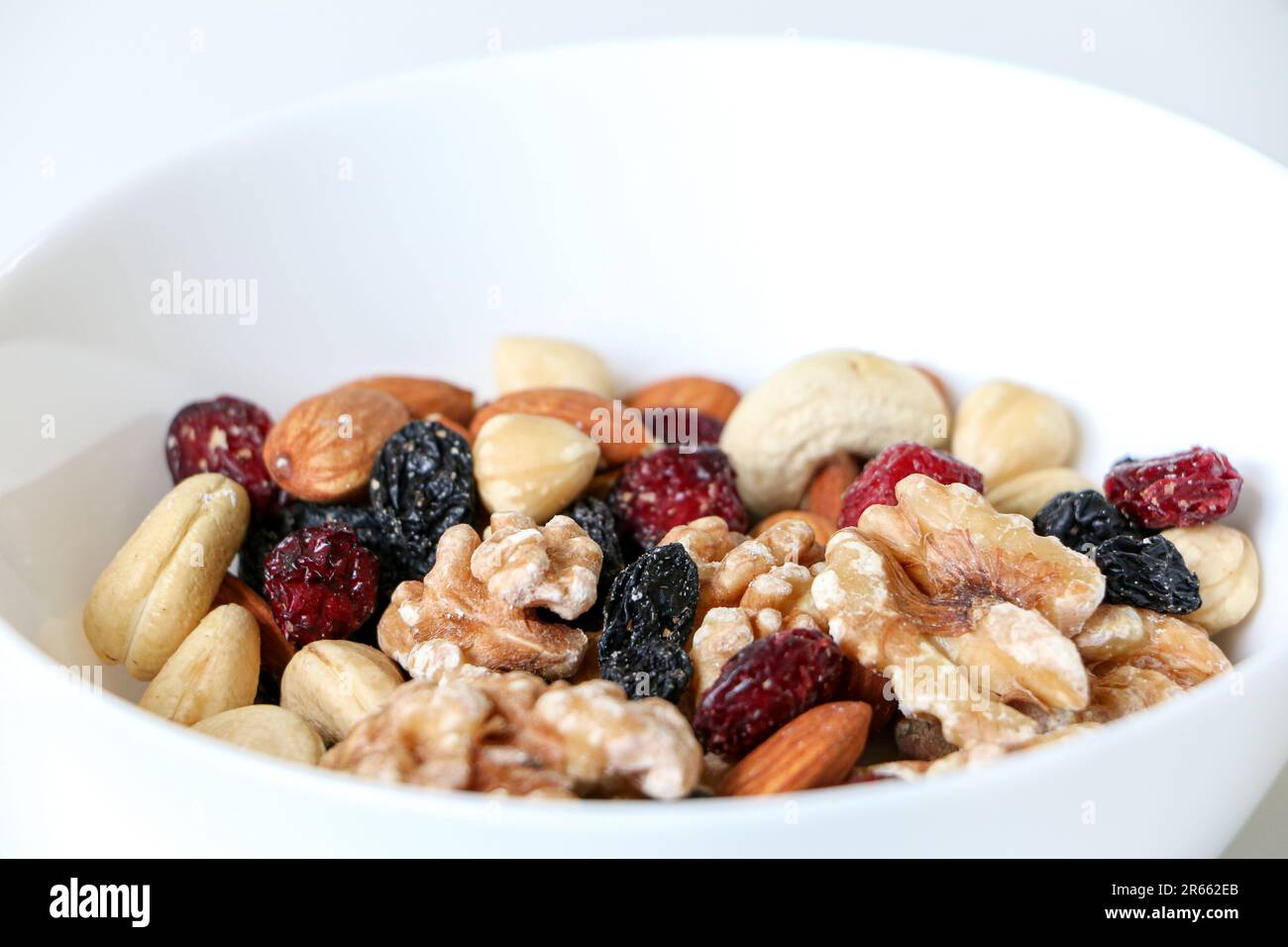 Close up of mixed nuts and dried fruits consisting of almonds, walnuts, hazelnuts, cashew nuts, raisins and cranberries with copy space above, healthy Stock Photo