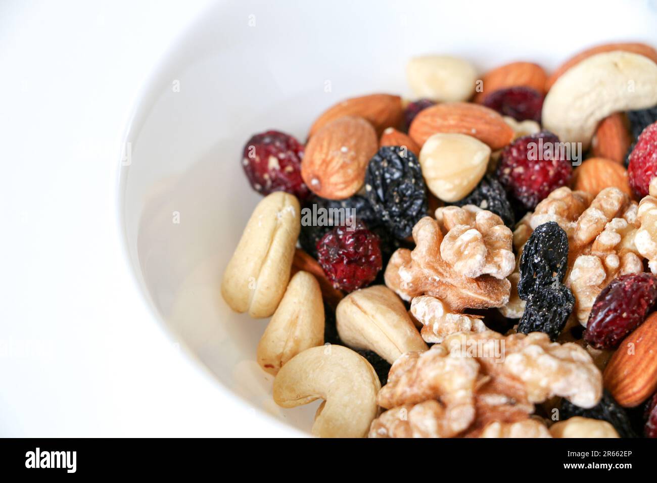 Healthy eating and living concept, close up of mixed nuts and dried fruits of almonds, walnuts, hazelnuts, cashew nuts, raisins and cranberries in a w Stock Photo