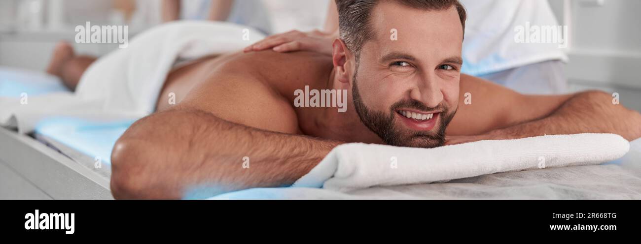Happy mature man undergoes massage procedure with professional chiropractics in clinic Stock Photo