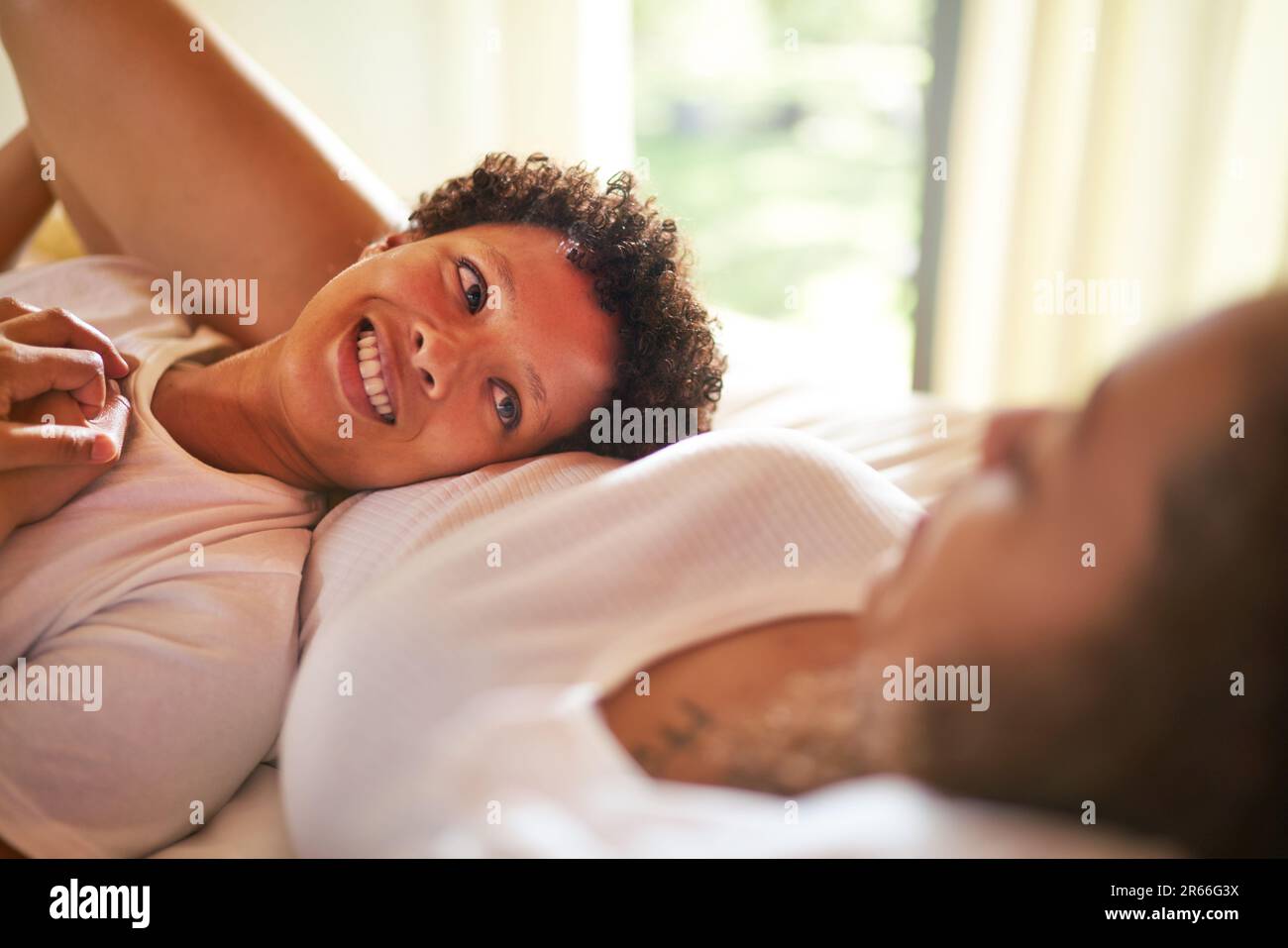 Close up happy lesbian couple cuddling and talking on bed Stock Photo
