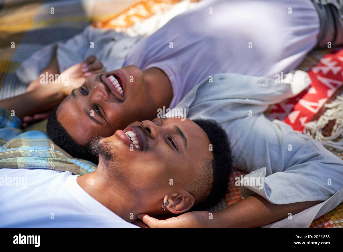 Close up happy, affectionate young gay male couple laying on blanket Stock Photo