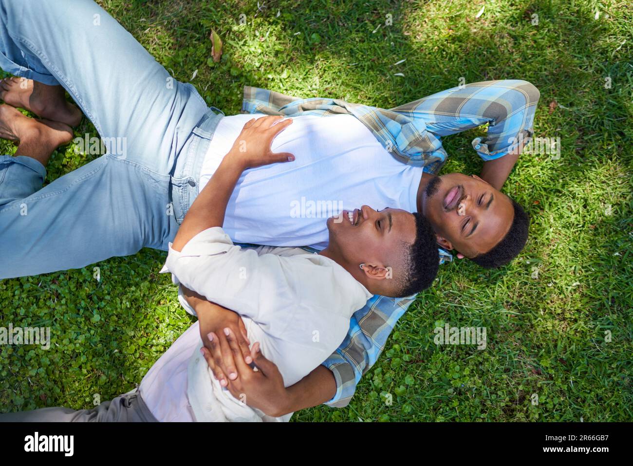 View from above happy, affectionate gay male couple laying in grass Stock Photo