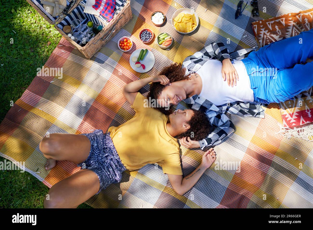 View from above happy lesbian couple laying on picnic blanket Stock Photo