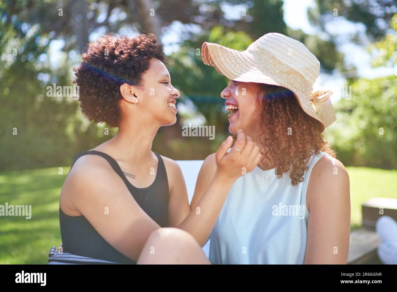 Happy, affectionate lesbian couple laughing in sunny summer backyard Stock Photo