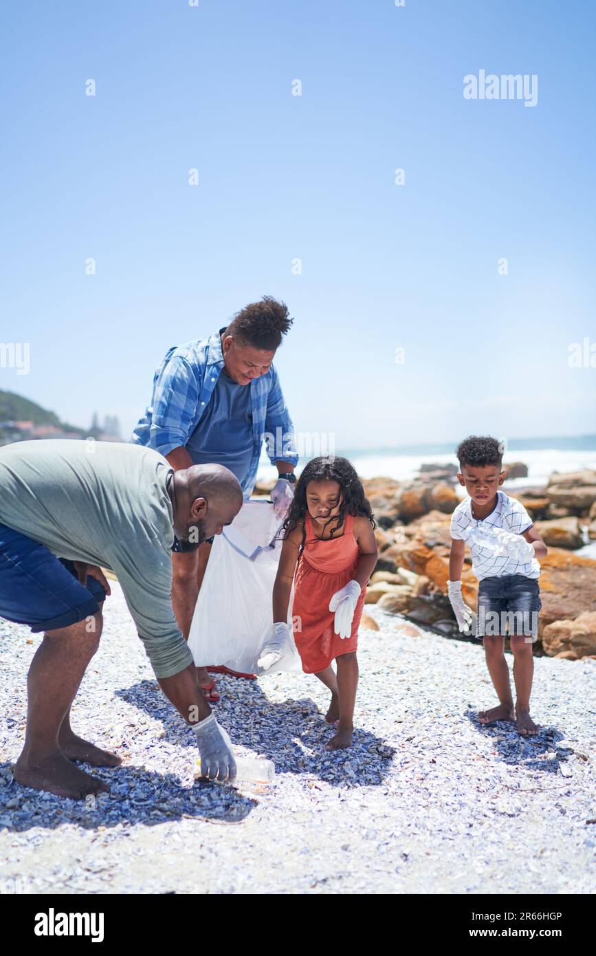 Family volunteering, cleaning litter from sunny summer beach Stock Photo