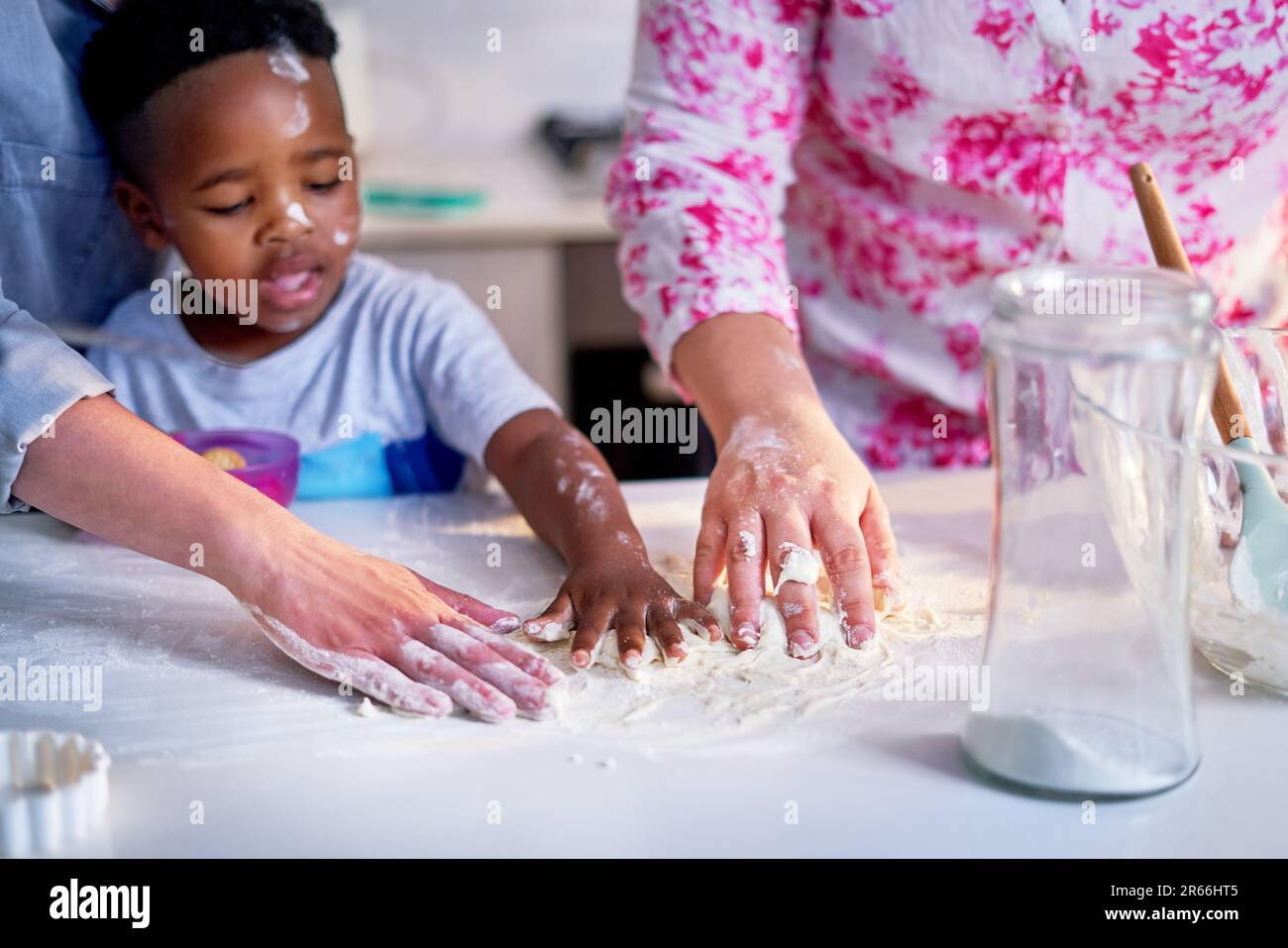 Lesbian couple and son baking, spreading flour on kitchen counter Stock Photo