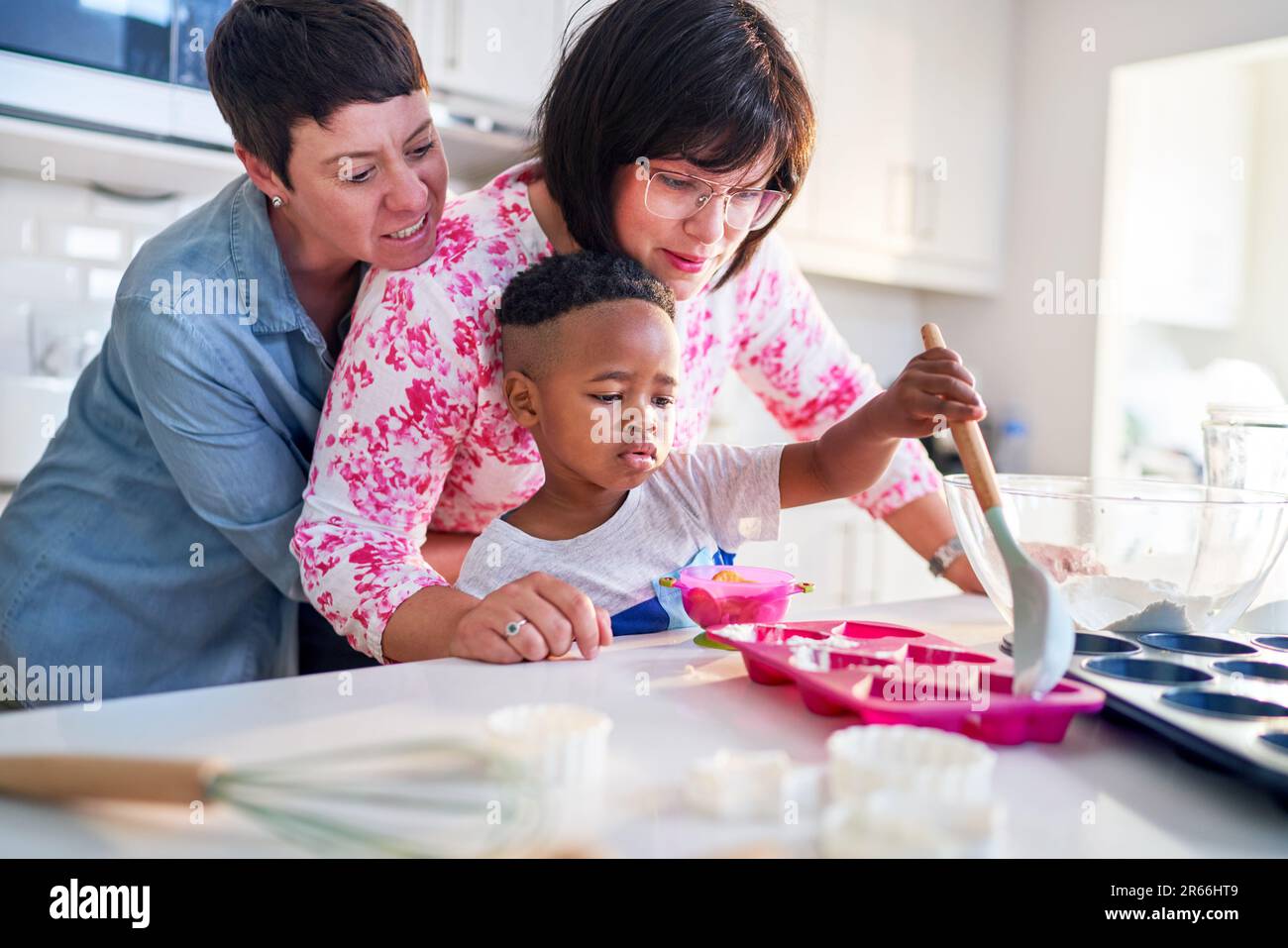 Lesbian couple and son baking heart-shape cupcakes in kitchen Stock Photo