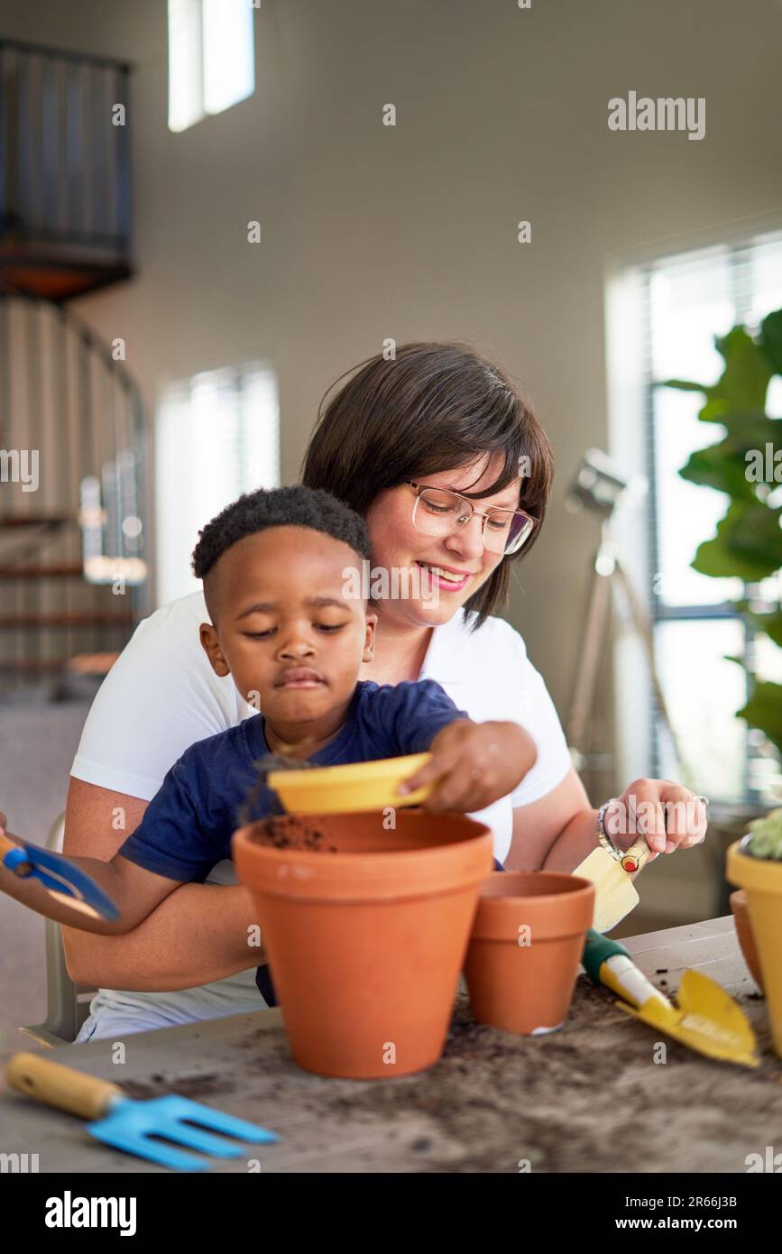 Mother and son planting in flowerpots at home Stock Photo