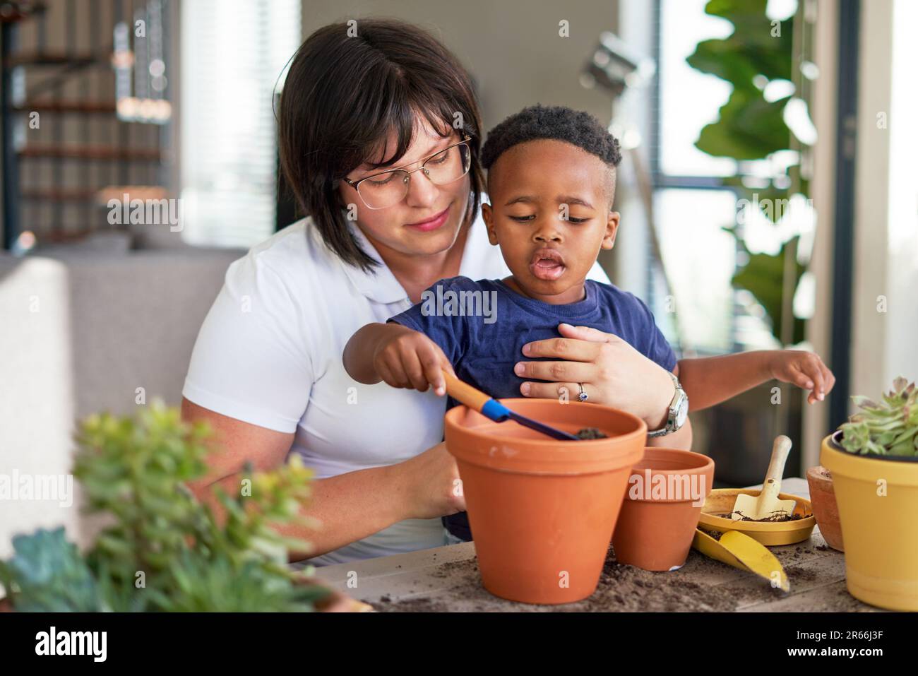 Mother and son planting plants in flowerpots on patio Stock Photo