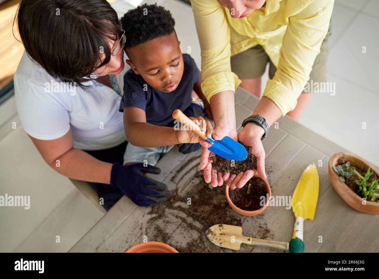 Lesbian couple and son digging in dirt, planting in flowerpots Stock Photo