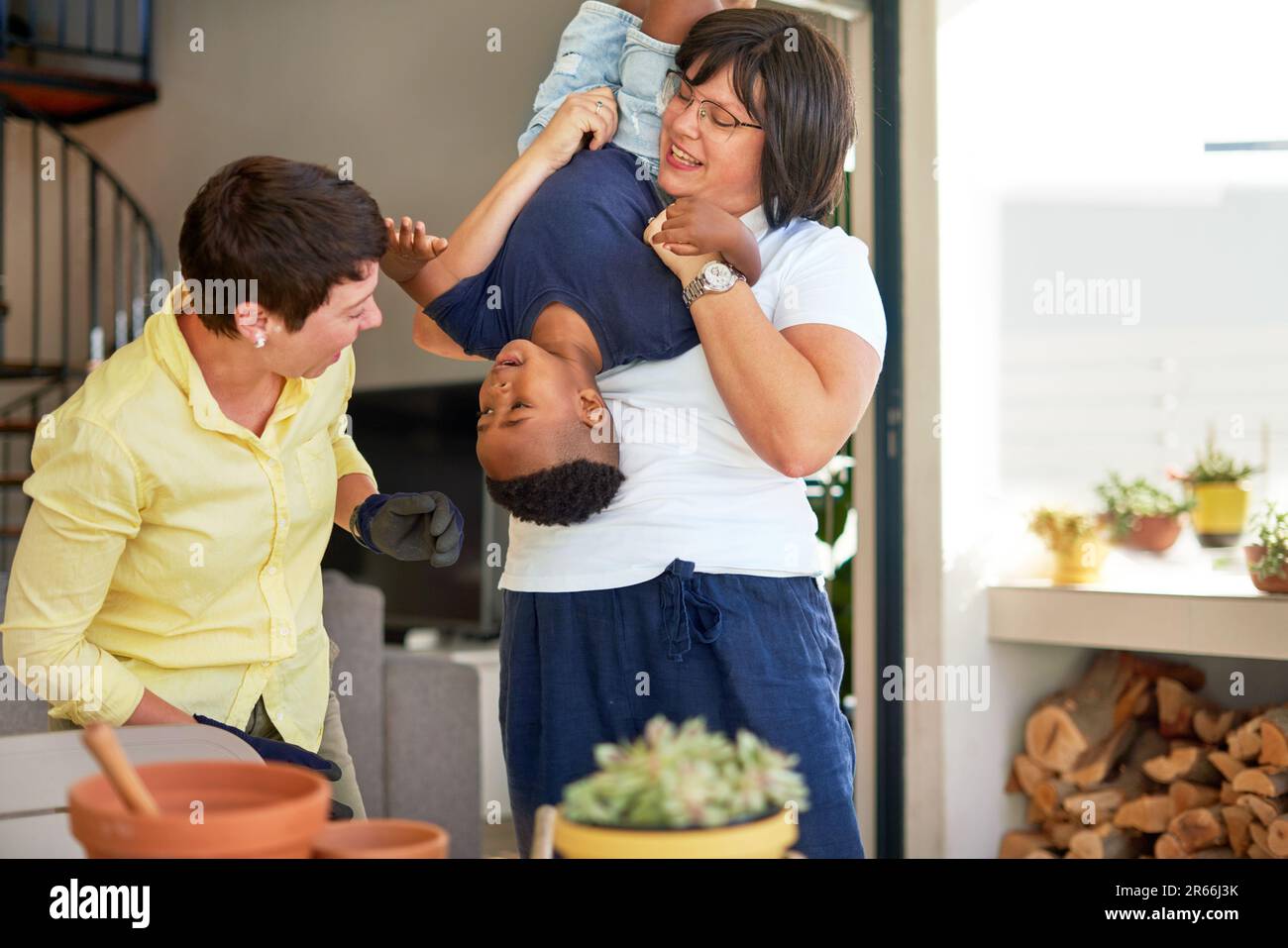 Happy, playful lesbian couple playing with son on patio Stock Photo