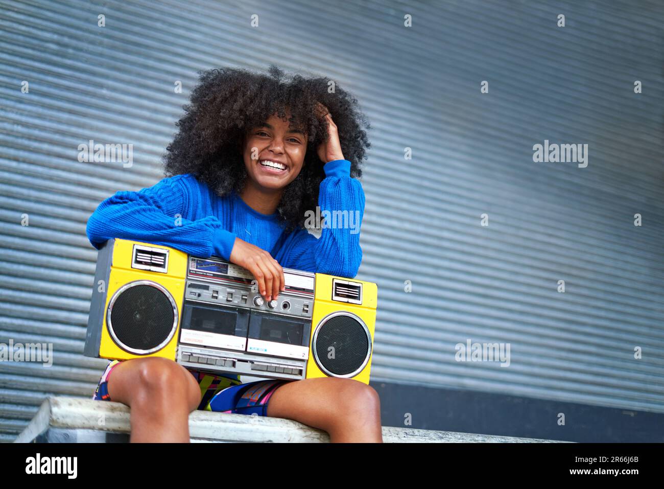 Portrait happy, cool young woman with boom box in alley Stock Photo