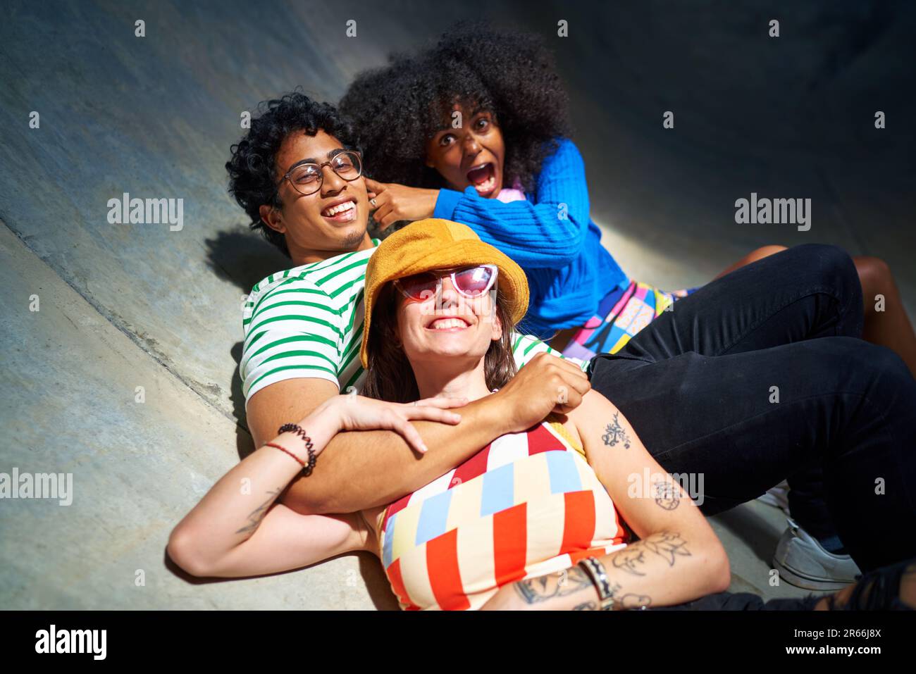 Portrait happy, carefree young friends laying on sports ramp Stock Photo